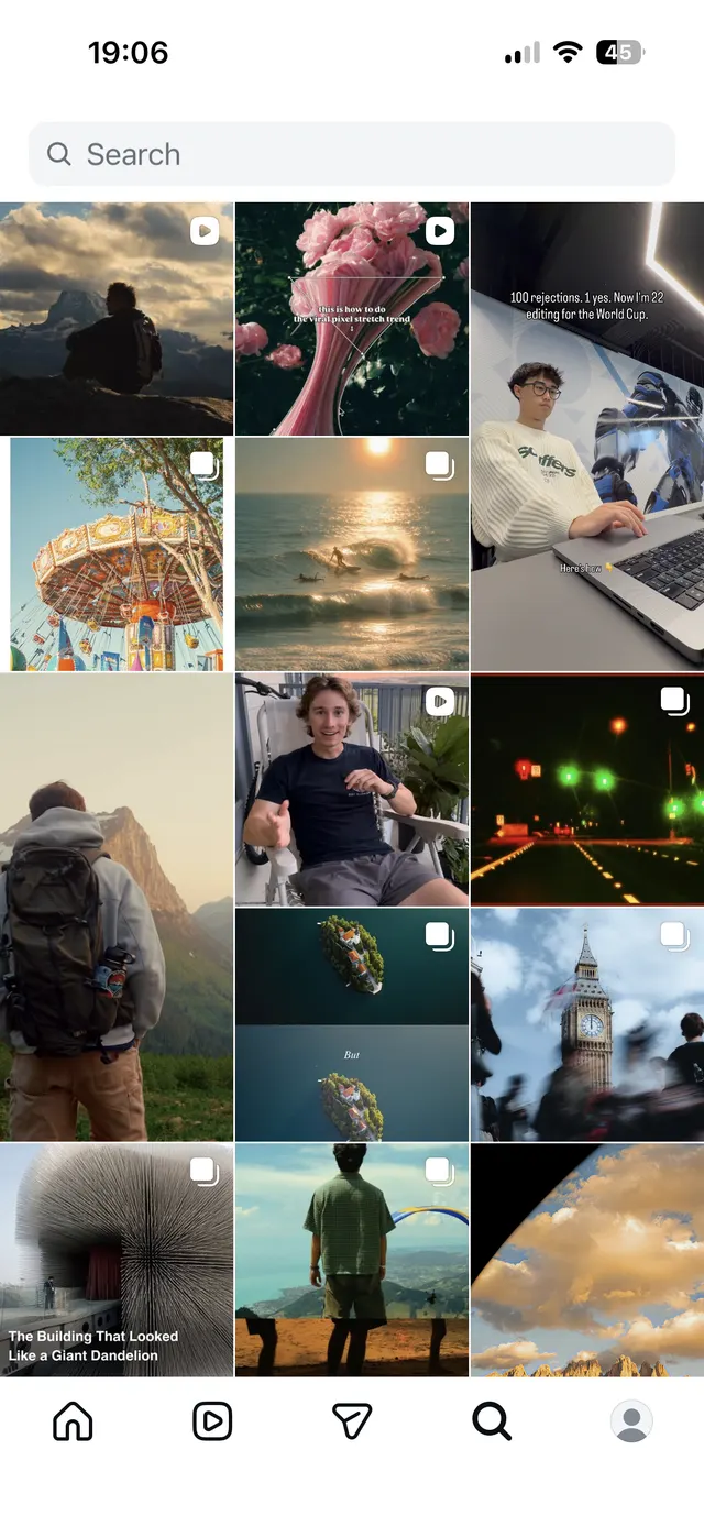 Mobile social app screen with a search bar at the top and a masonry-style grid of square media thumbnails below, some marked as videos or multi-item posts, plus a bottom navigation bar.