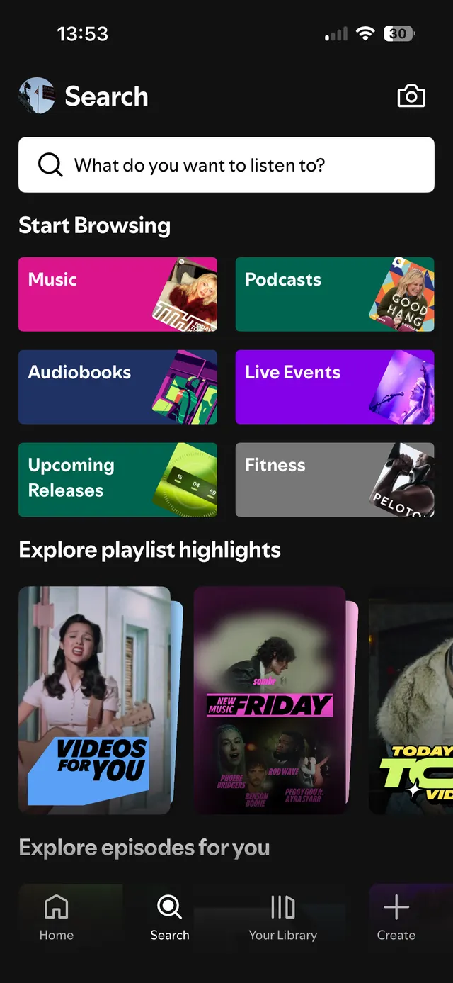 Mobile app search screen with a search bar, browsing categories like Music, Podcasts, Audiobooks, Live Events, Upcoming Releases, Fitness, playlist highlights with album images, and bottom navigation bar with Home, Search, Your Library, and Create icons.