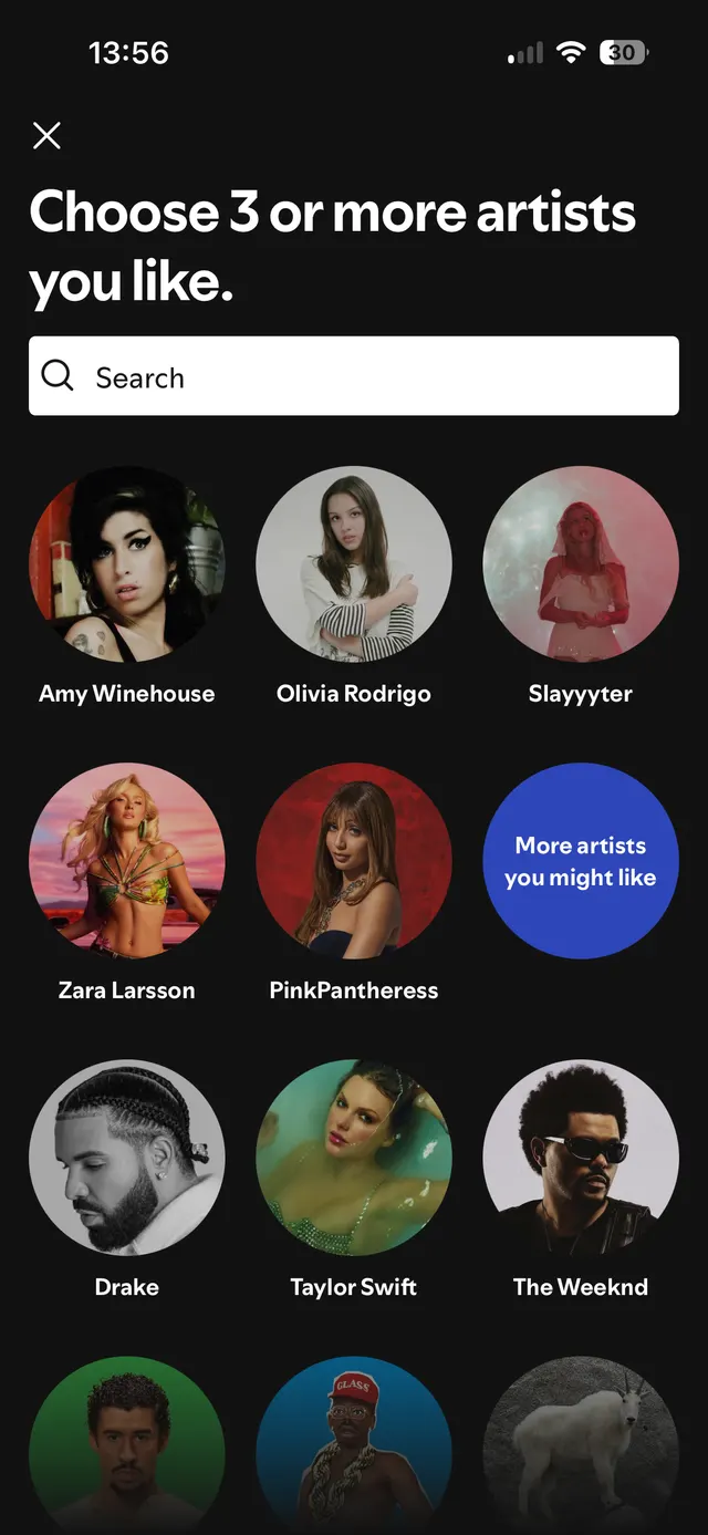 Screen to choose three or more musical artists you like, showing a search bar and circular images of various artists including Amy Winehouse, Olivia Rodrigo, Slayyyter, Zara Larsson, PinkPantheress, Drake, Taylor Swift, The Weeknd, and others, with a button labeled More artists you might like.