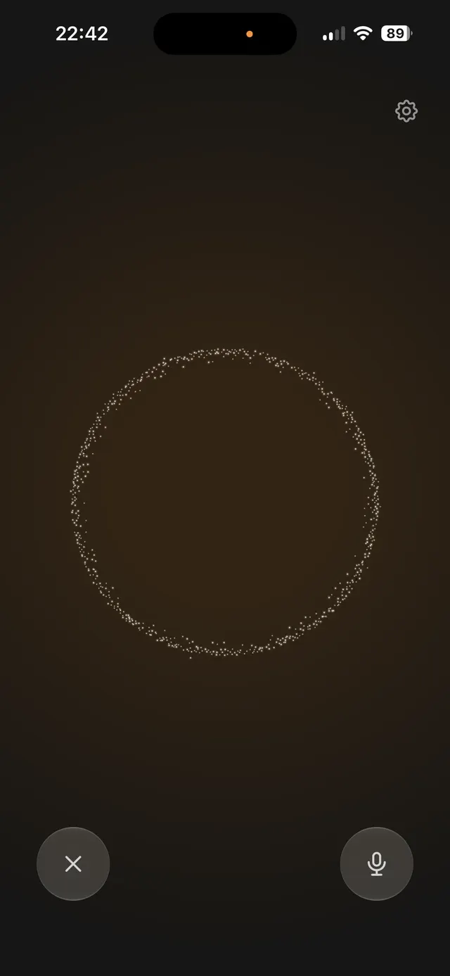 Dark mobile screen with a large dotted animated circle in the center, an X cancel button at bottom left, a microphone button at bottom right, and a settings gear at top right.